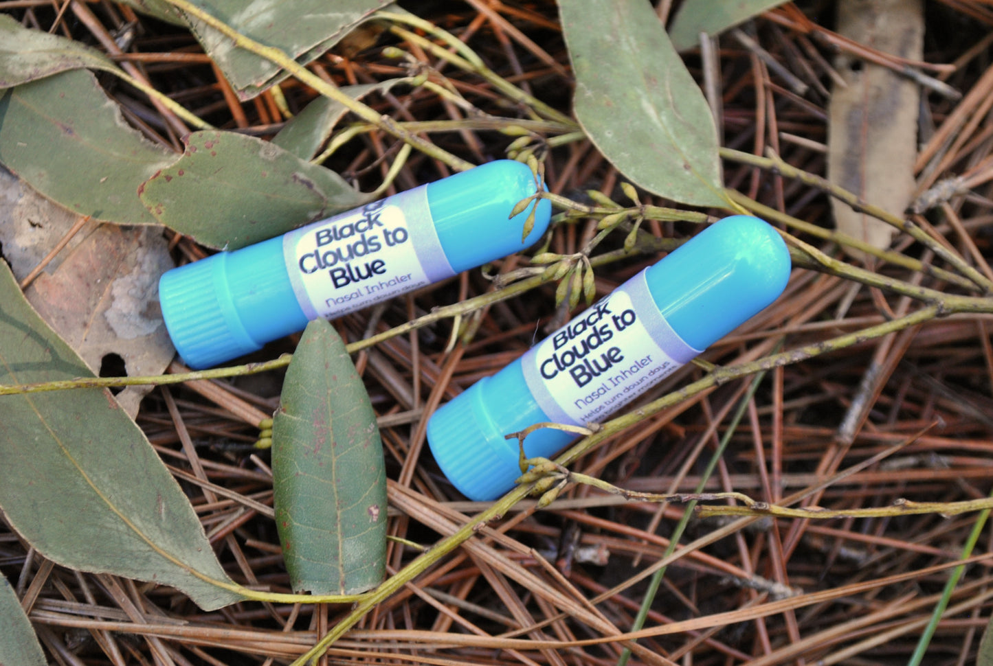 Black Clouds Inhaler tube, natural essential oil aromatherapy for low mood support on a natural background of leaves and twigs.