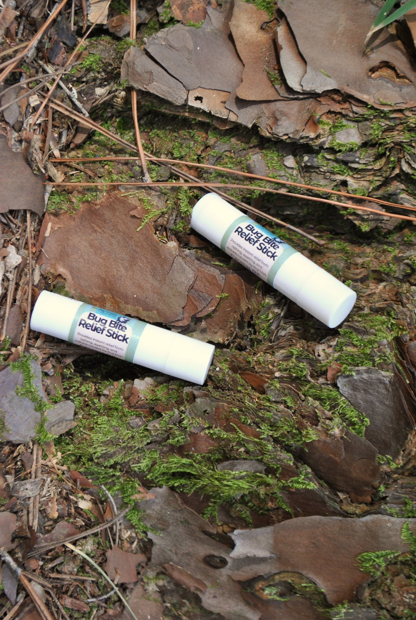 Bug Bite Relief Stick tube, natural soothing balm for insect bites on a natural background with leaves and moss.