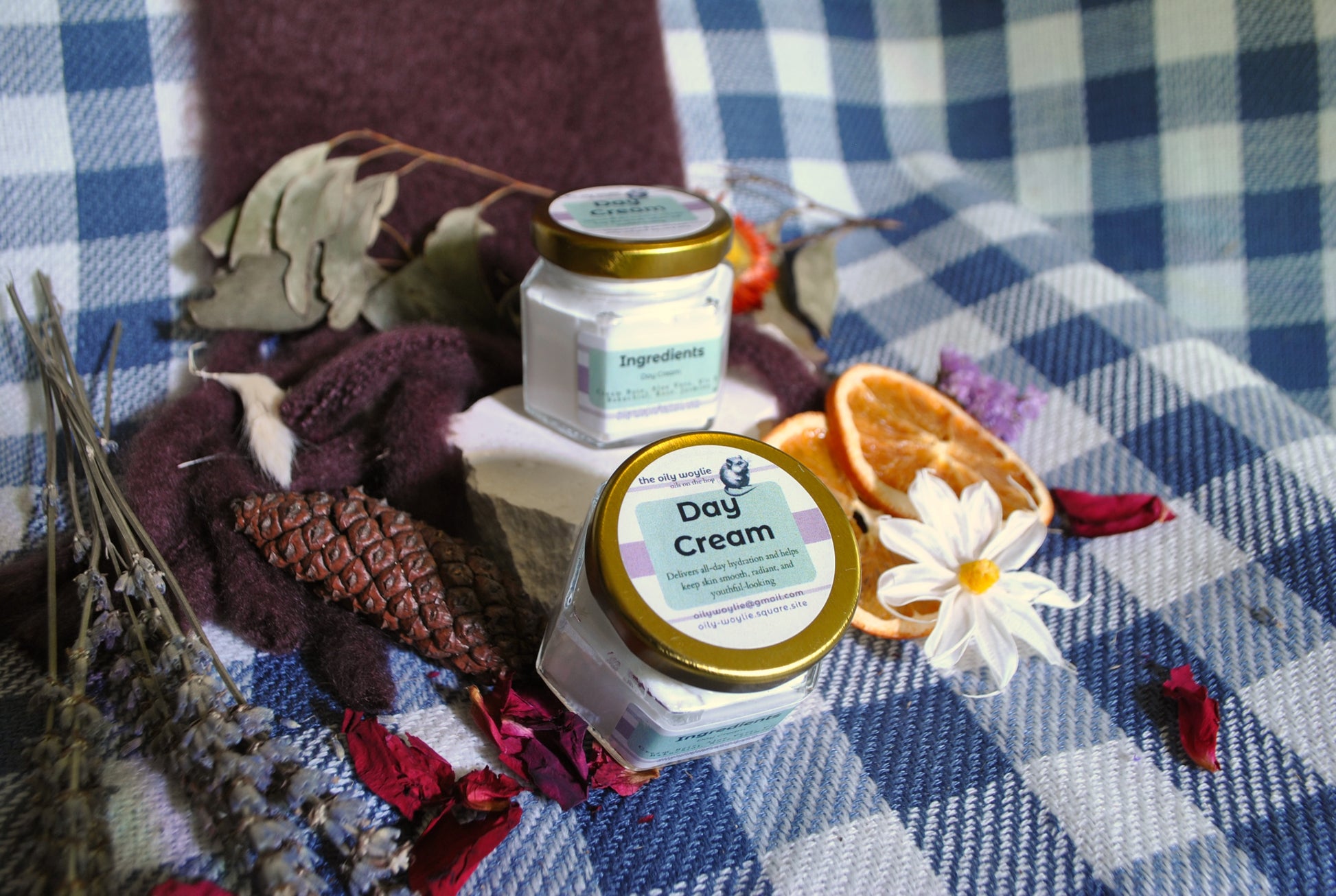 Day Cream jar, natural daily face cream for hydration and skin nourishment on a checkered fabric background with dried flowers and leaves.