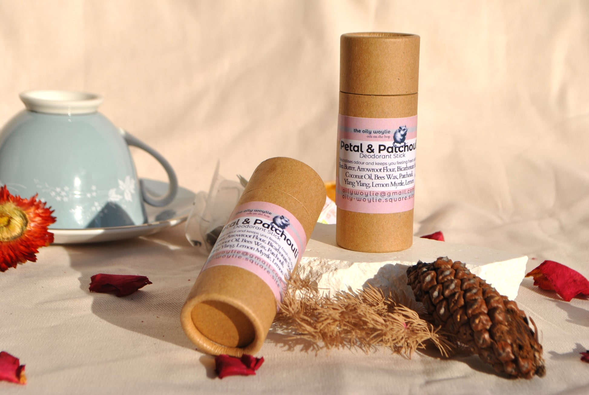 Deodorant stick Petal & Patchouli bottle, natural floral deodorant on a surface with decorative elements like a teacup and flowers.