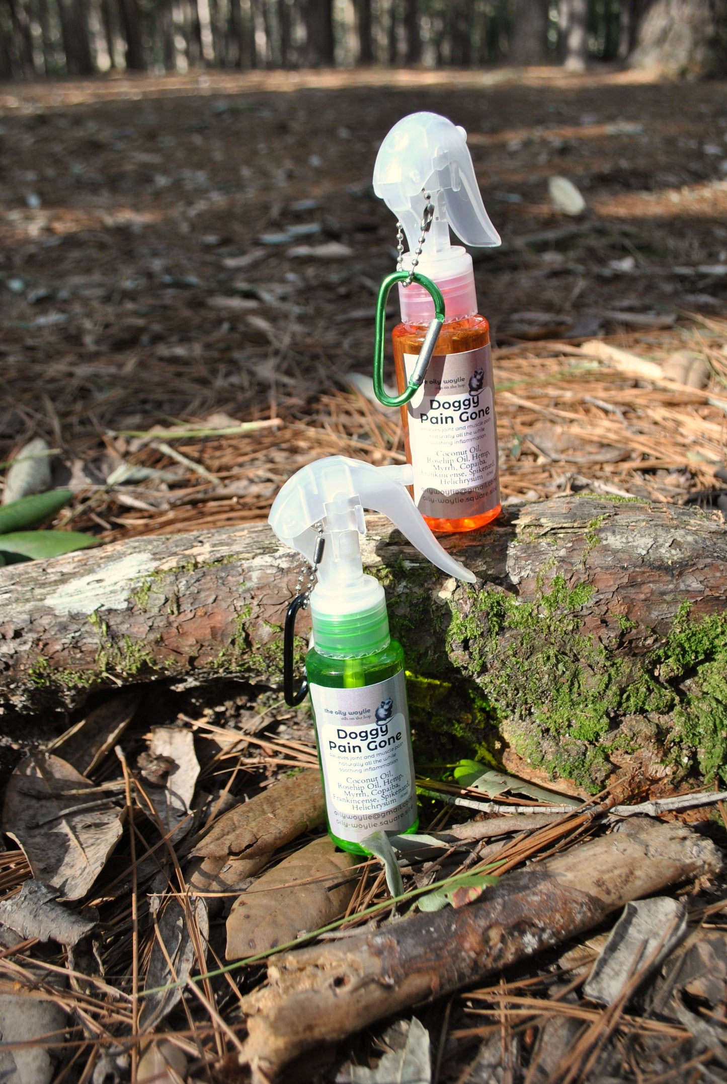 Doggy Pain Gone spray bottle, natural relief spray for dogs with sore muscles and joints on a log in a forest setting.