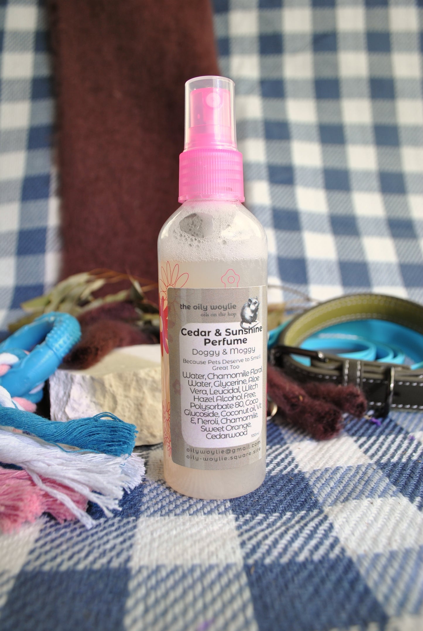 Doggy Perfume Cedar & Sunshine spray bottle, natural woody citrus deodorising spray for dogs on a checkered fabric background