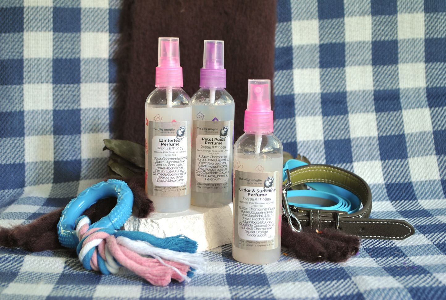 Trio of Doggy Perfume natural spray to keep dogs smelling freshon a checkered fabric background