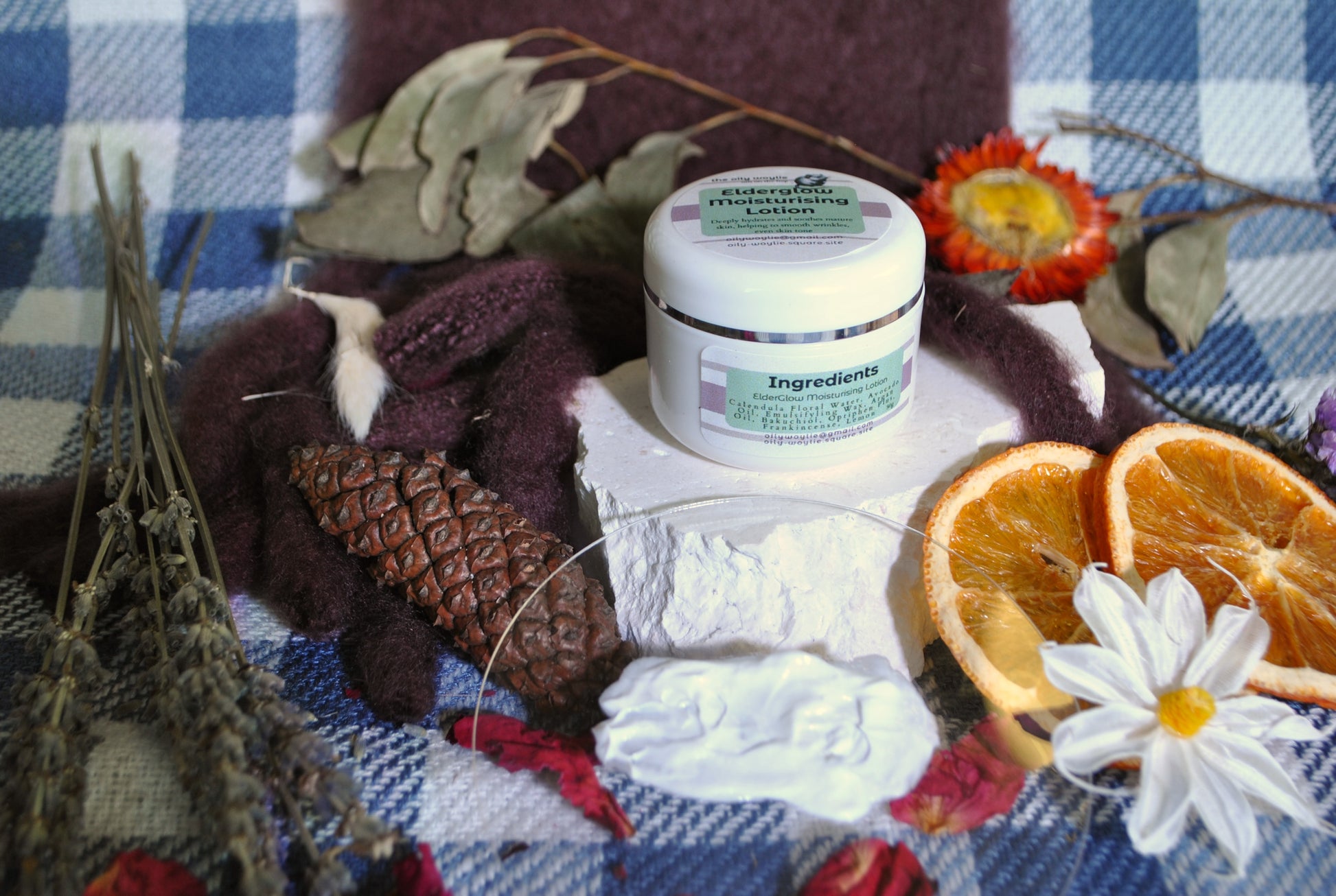 Elderglow Moisturising Lotion bottle, natural anti-aging lotion for soft and hydrated skin on a checkered fabric background with decorative elements.