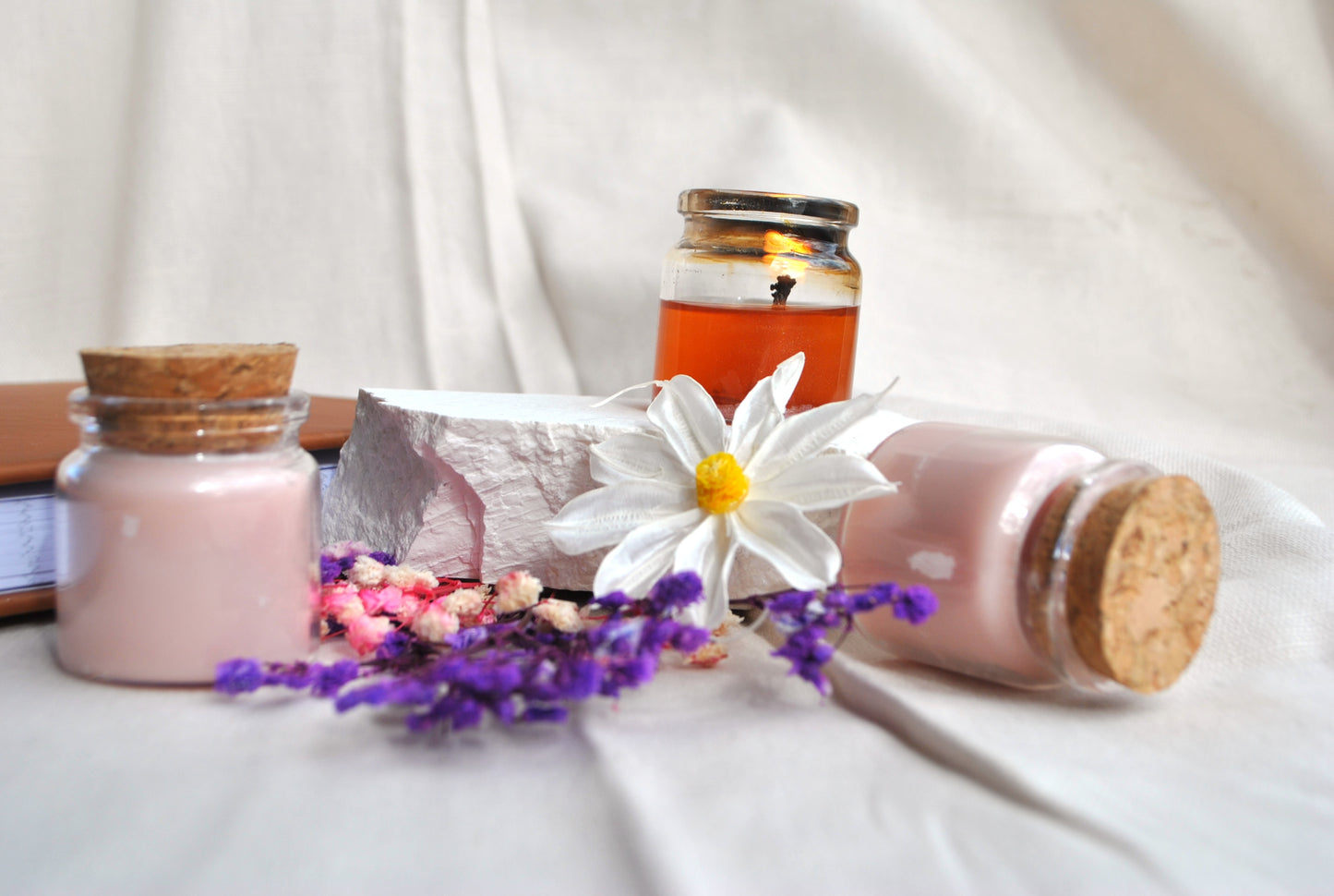 Enchanted Arbor natural soy tea lights, scented candles with calming forest aroma on a white fabric background with a daisy flower.