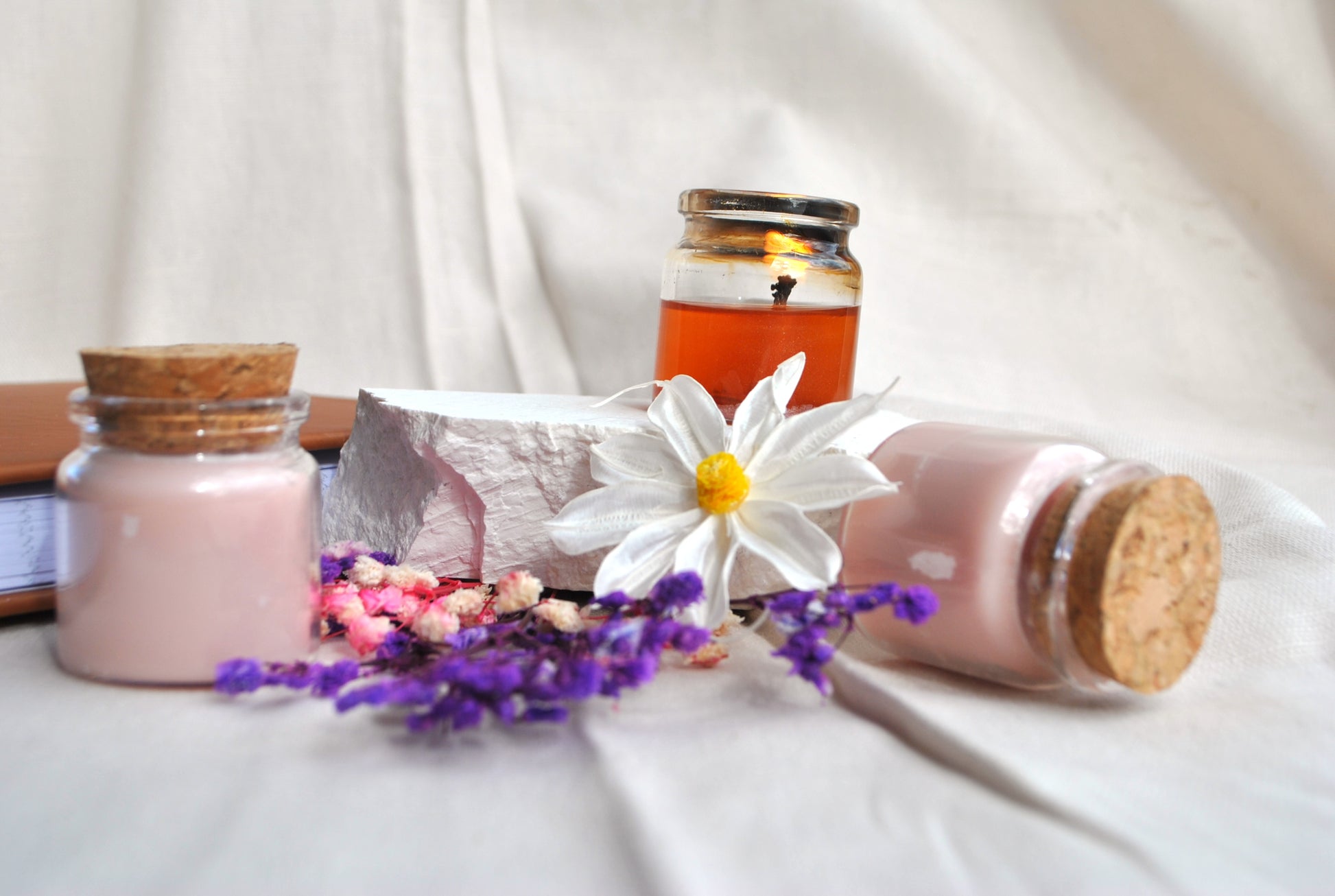 Enchanted Arbor natural soy tea lights, scented candles with calming forest aroma on a white fabric background with a daisy flower.