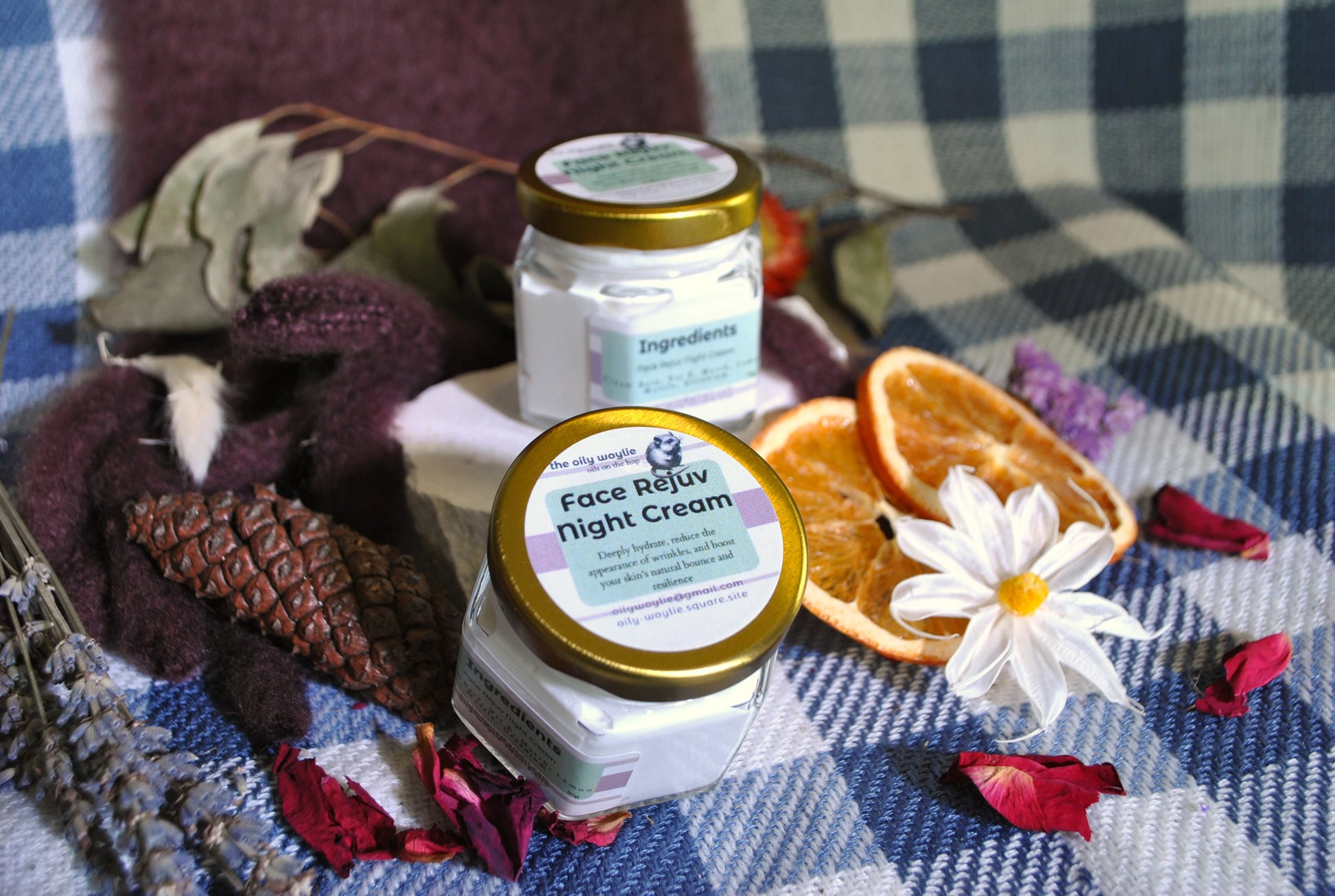 Face Rejuv Night Cream jar, natural night cream to rejuvenate and hydrate skin overnight on a checkered fabric background with dried oranges and flowers.