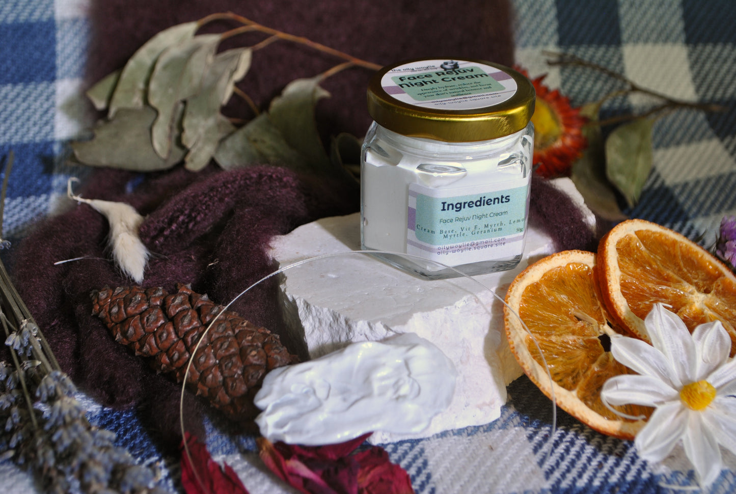 Face Rejuv Night Cream jar, natural night cream to rejuvenate and hydrate skin overnight on a checkered cloth with oranges and flowers