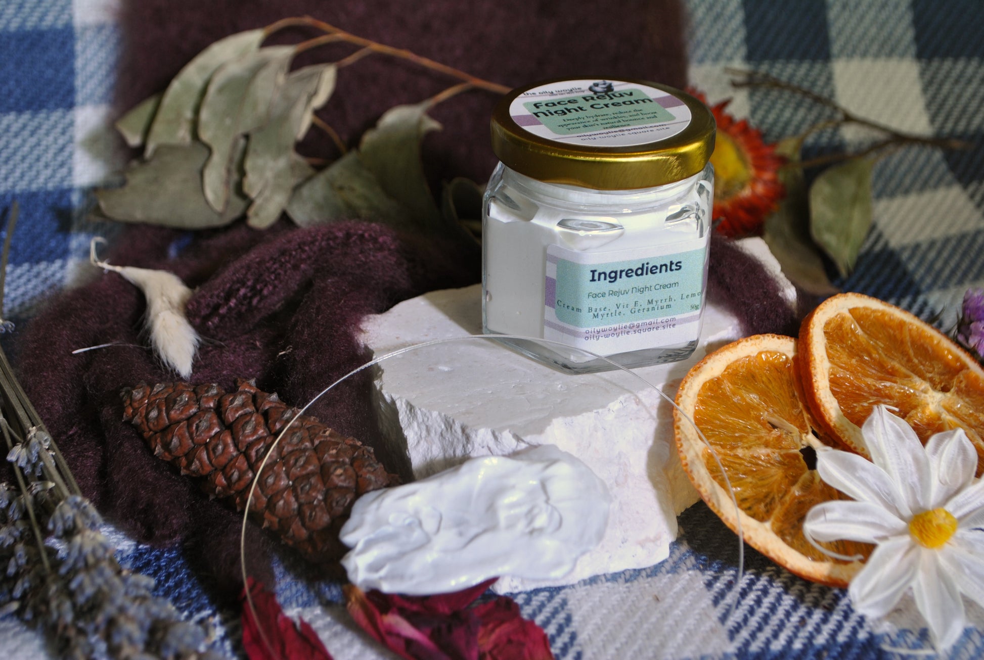 Face Rejuv Night Cream jar, natural night cream to rejuvenate and hydrate skin overnight on a checkered cloth with oranges and flowers