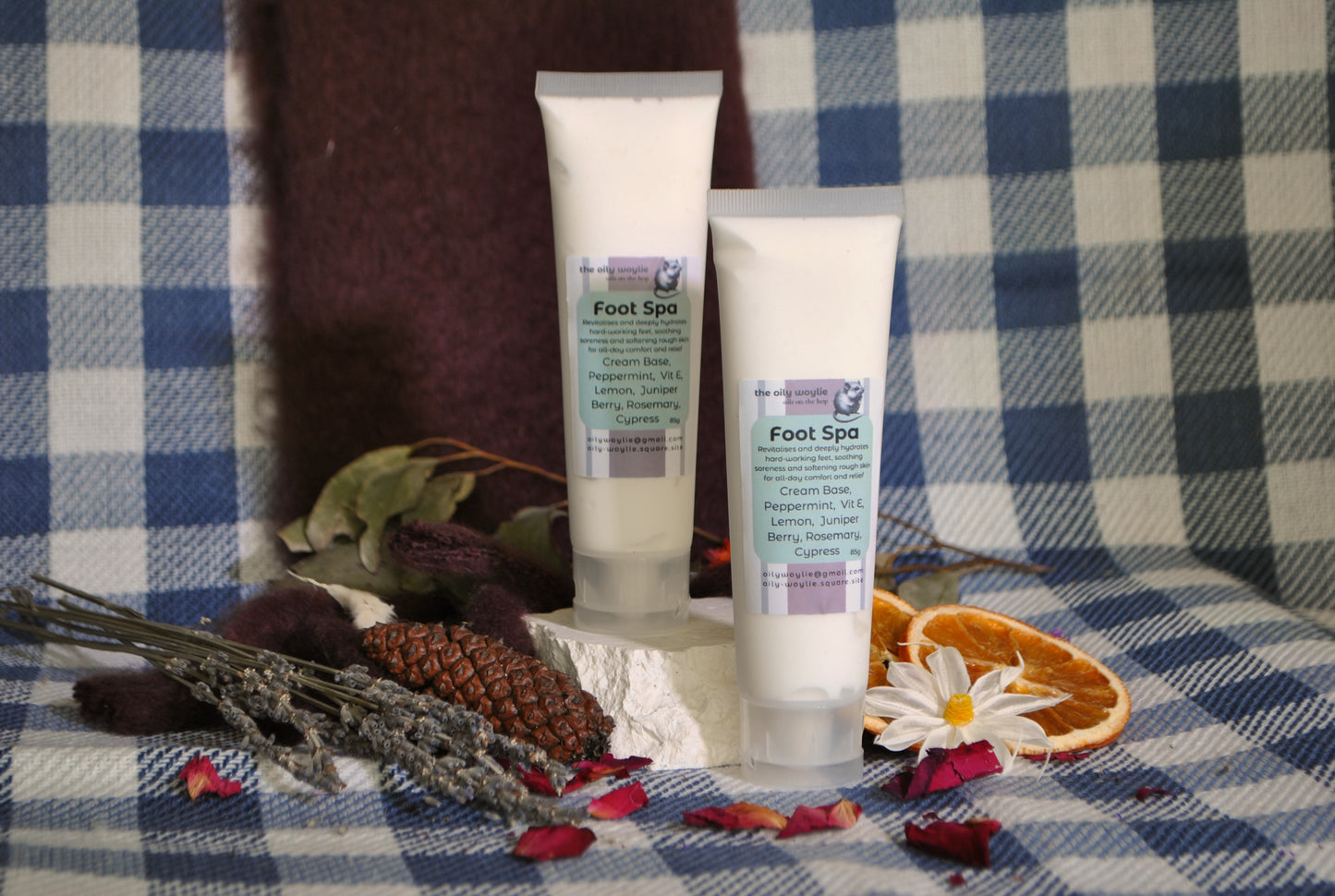 Foot Spa cream tube, natural foot rub with essential oils for relaxation and soft feet on a checkered fabric background with flowers and leaves.