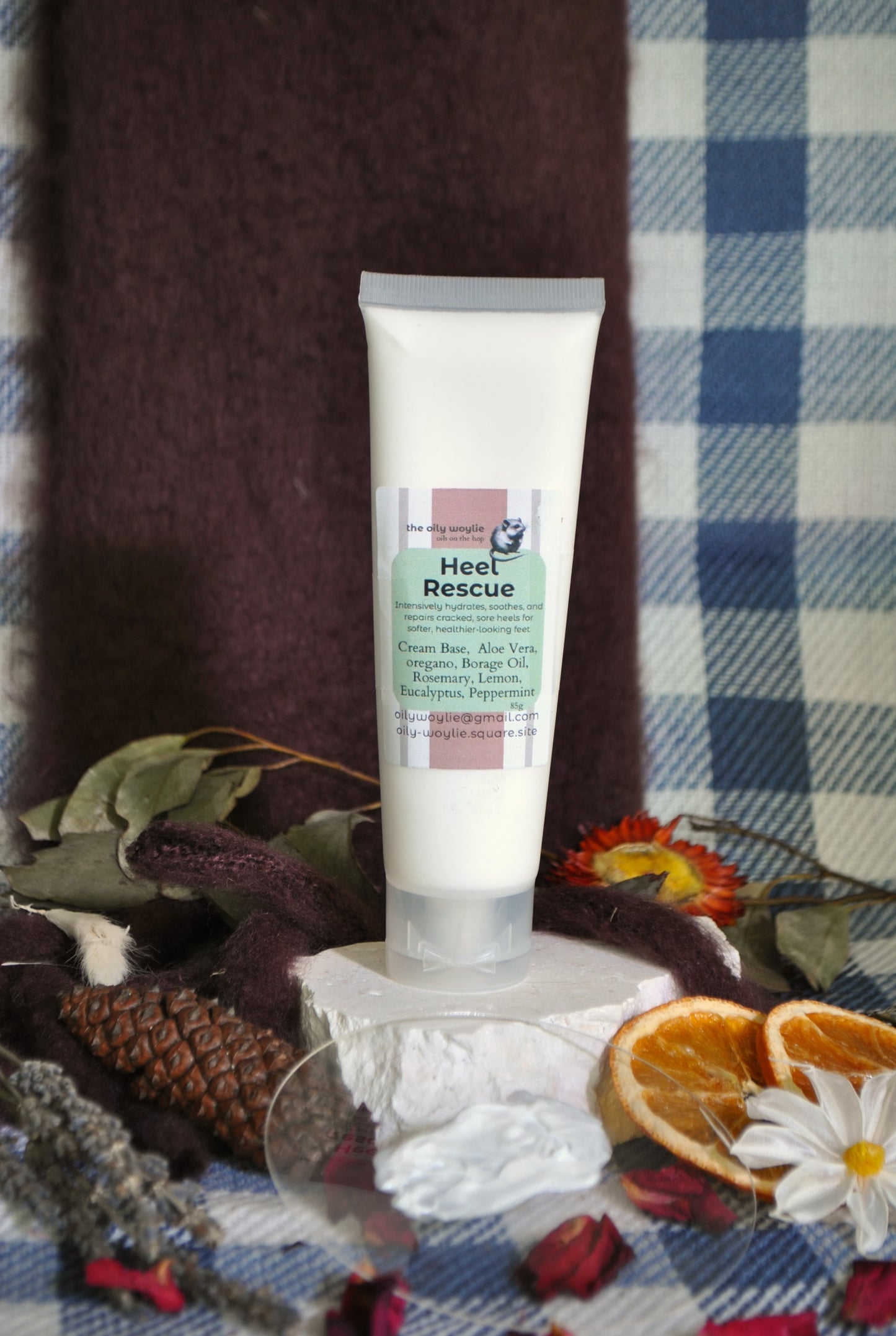 Heel Rescue cream jar, natural foot cream for cracked heels and dry feet on a checkered fabric background with natural elements.