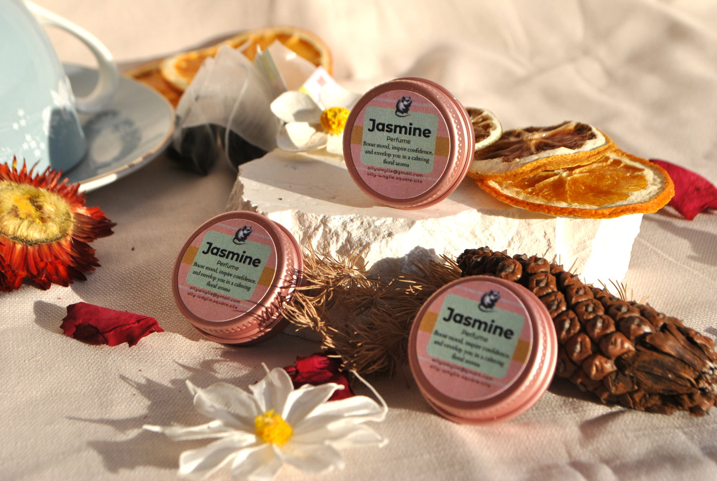 Jasmine Perfume, natural floral fragrance with jasmine scent with dried oranges, flowers, and a teacup on a light background