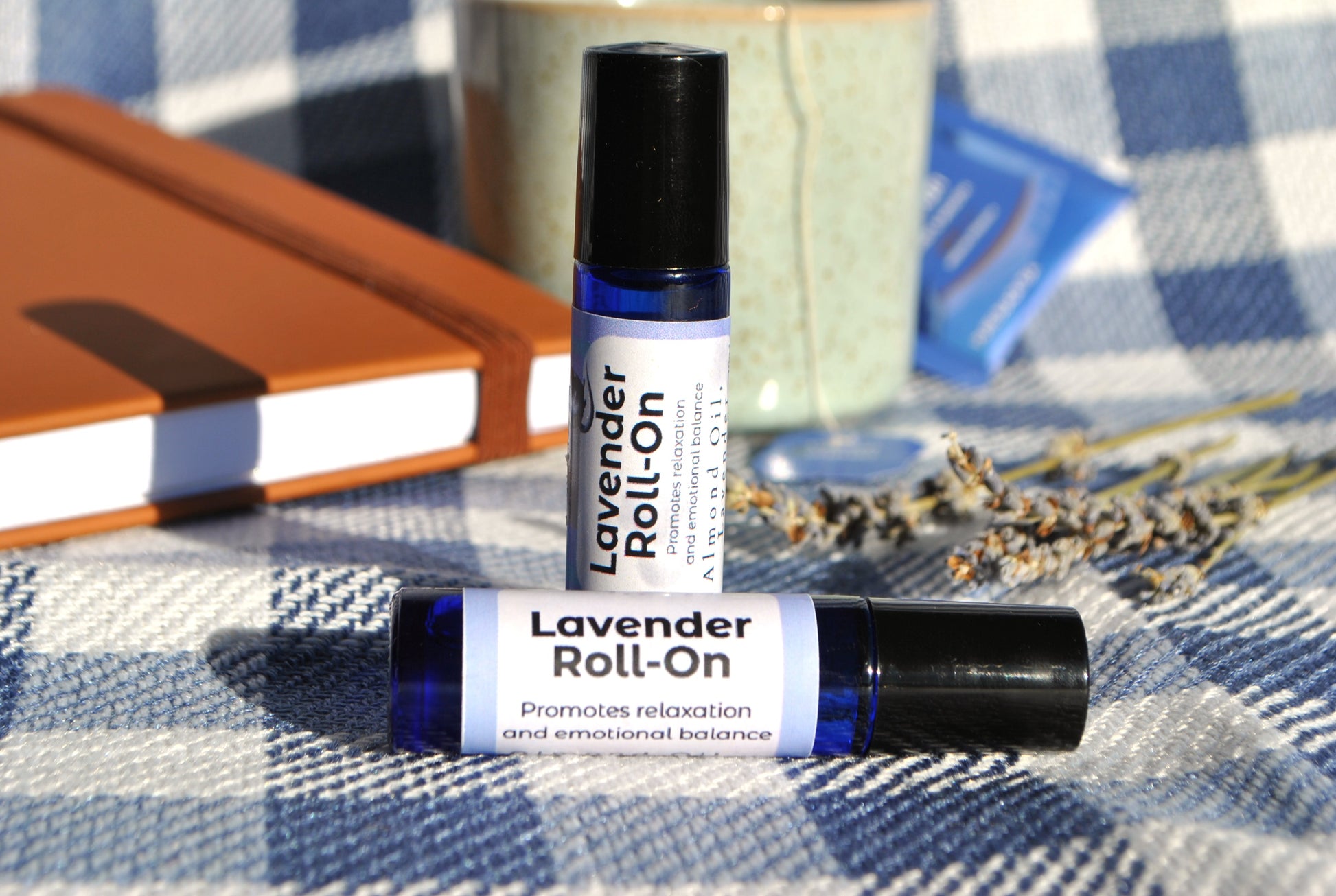 Lavender Roll essential oil roller blend, natural calming support Two roll-on bottles on a checkered fabric background