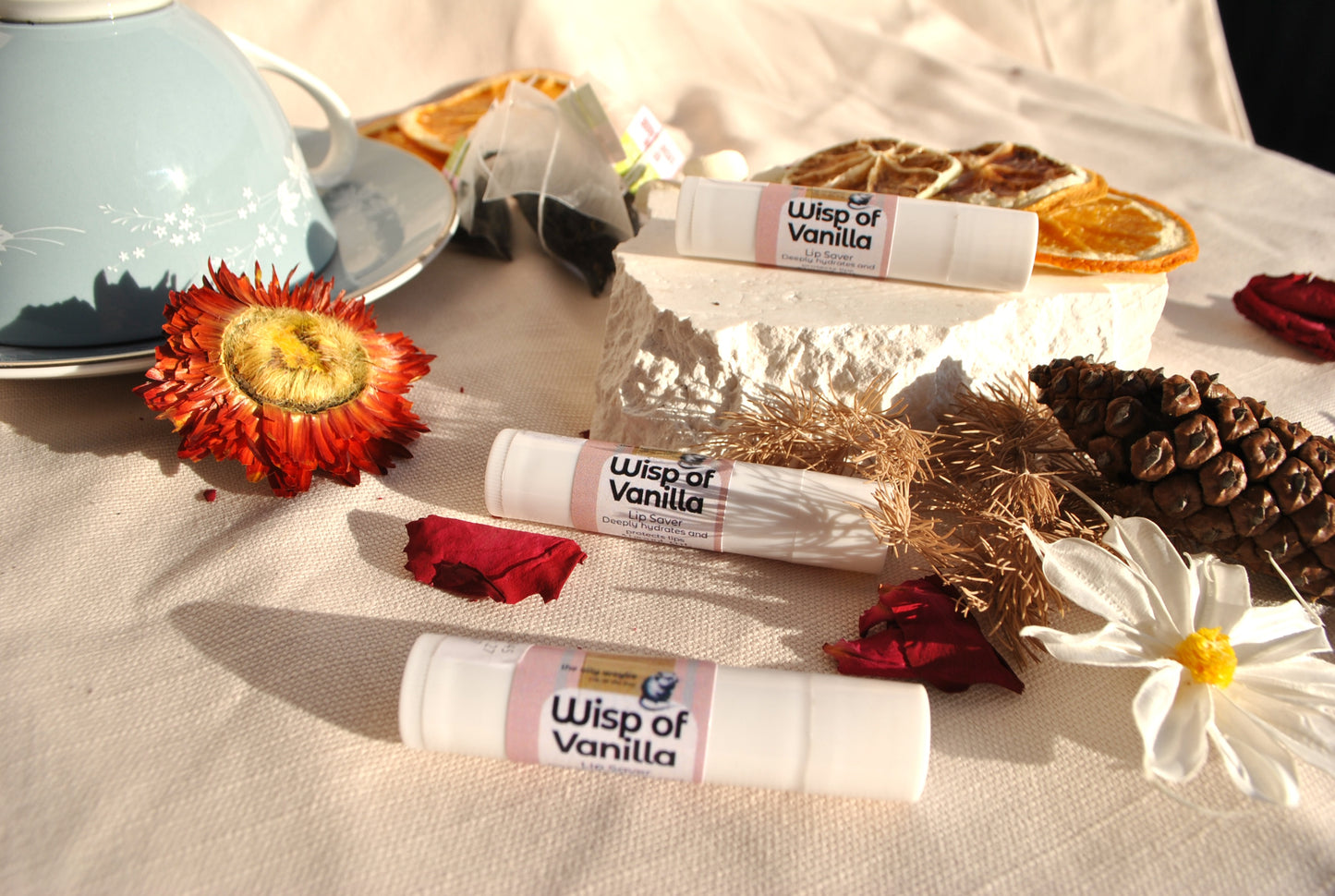 Lip Saver Wisp of Vanilla balm stick, soothing natural lip balm with decorative elements on a textured surface