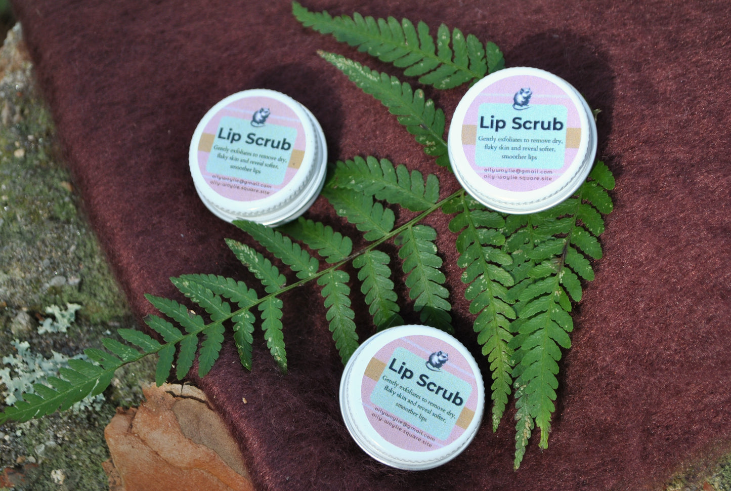 Lip Scrub jar, natural exfoliating scrub for soft and smooth lips with bush background with green leaves on a textured surface