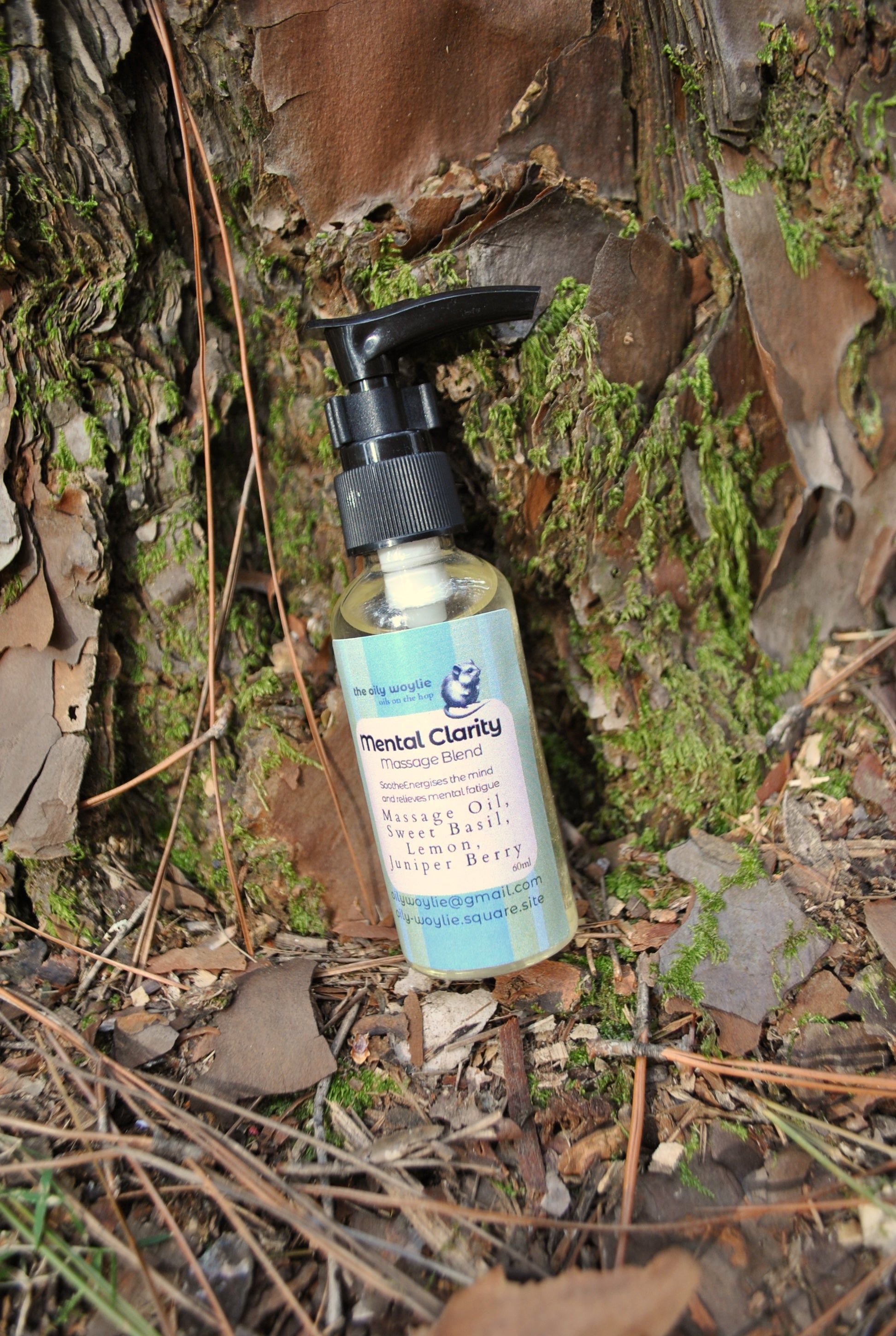 Mental Clarity Massage essential oil blend bottle, natural support for focus and concentration on a natural background with moss and leaves.