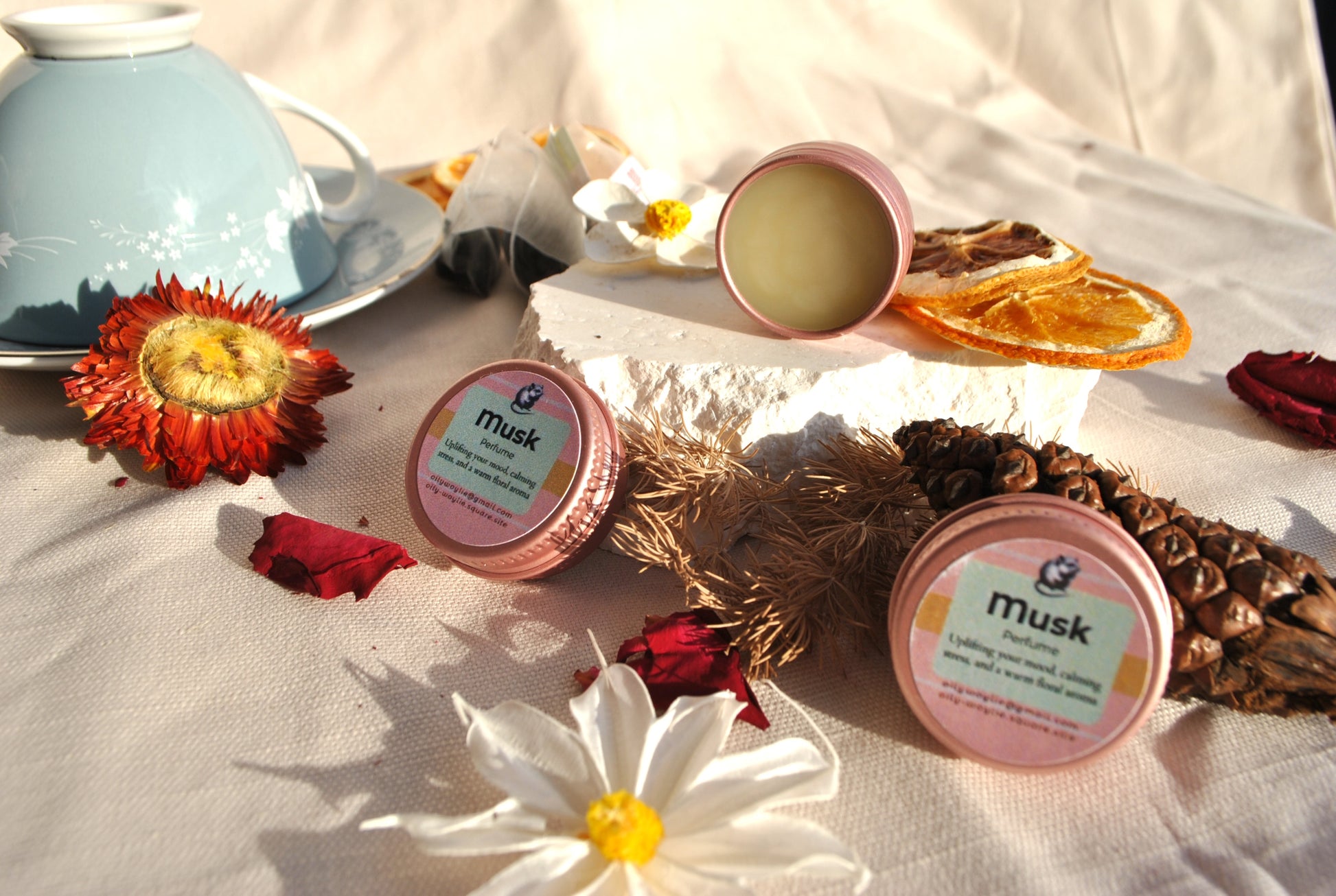 Musk Perfume, natural earthy fragrance with musk scent on a textured surface with flowers and leaves.