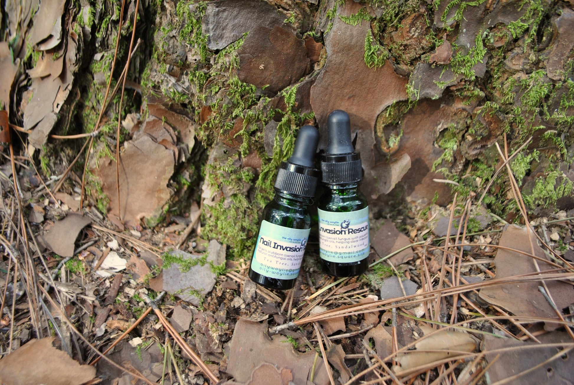 Nail Invasion Rescue bottle, natural nail and cuticle treatment for fungal support on a forest floor with moss and leaves.