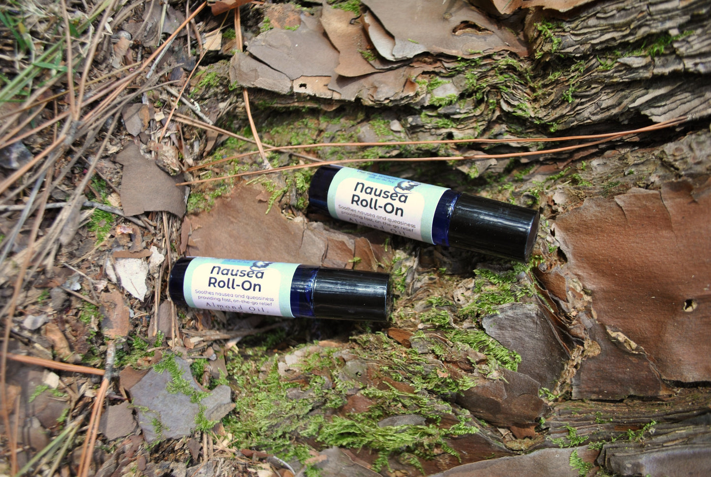 Nausea Roll essential oil roller blend, natural support for nausea and upset stomach on a natural background with leaves and wood.