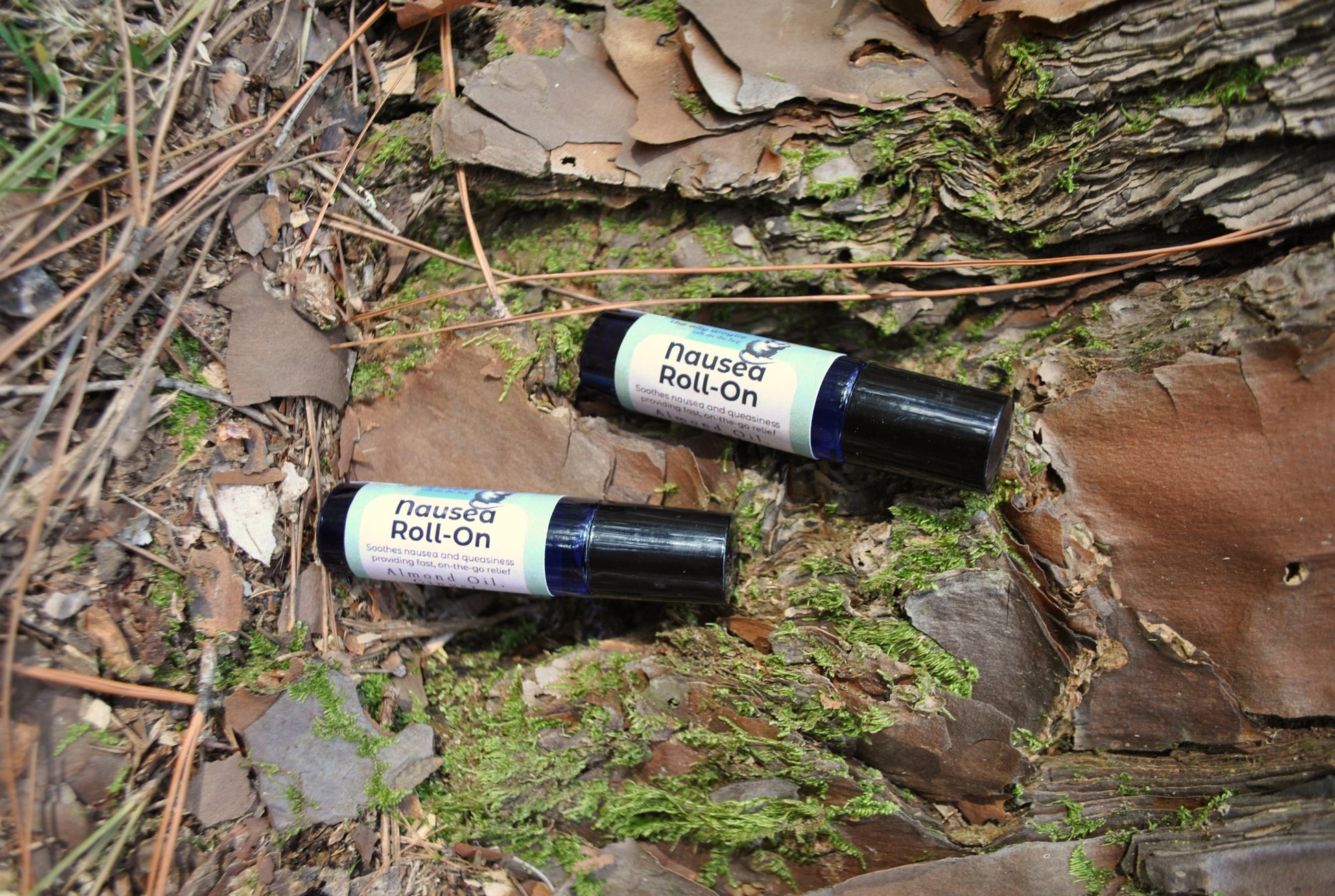 Nausea Roll essential oil roller blend, natural support for nausea and upset stomach on a natural background with leaves and wood.