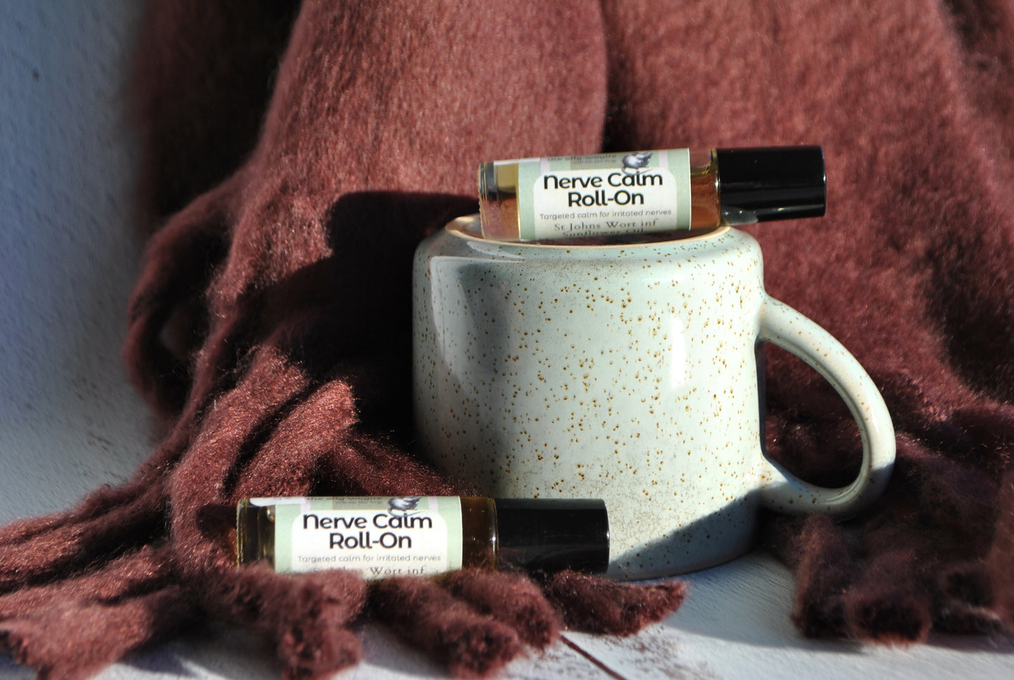 Nerve Calm essential oil blend roller bottle, natural calming support for nerve pain sitting on mug