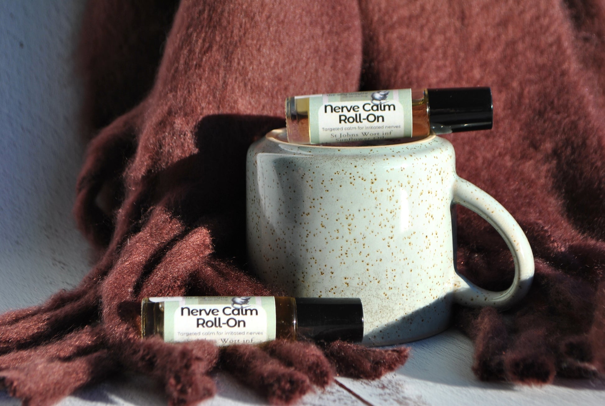 Nerve Calm essential oil blend roller bottle, natural calming support for nerve pain sitting on mug