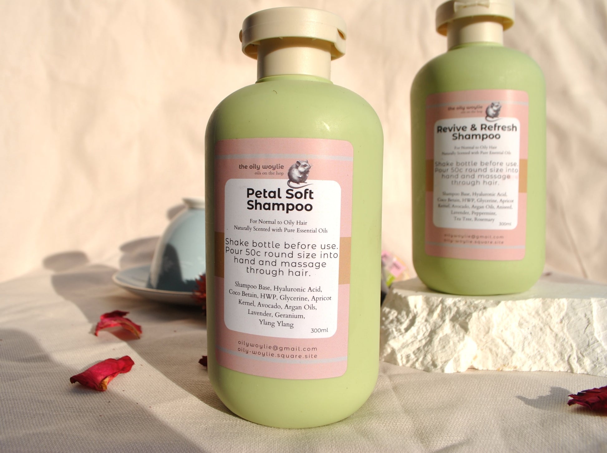 Revive & Refresh and Petal Soft natural shampoo bottles side by side, eco-friendly hair care on a textured surface with flowers and a bowl in the background.