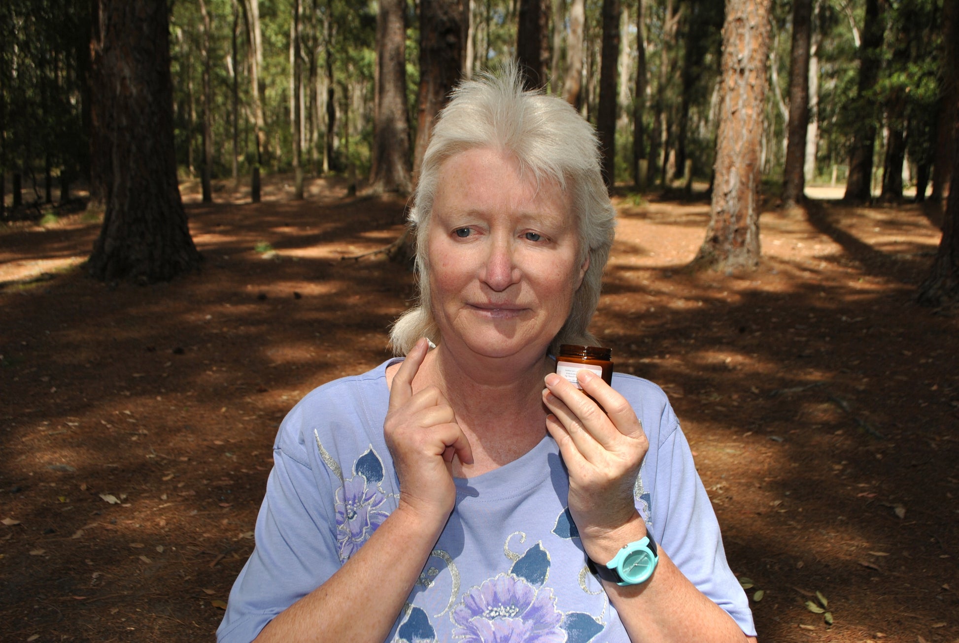 Person sitting outdoors in the Watagan Mountains applying The Oily Woylie Wound & Chafing Cream to a scrape on their neck — natural skin repair and protection for life in the bush.