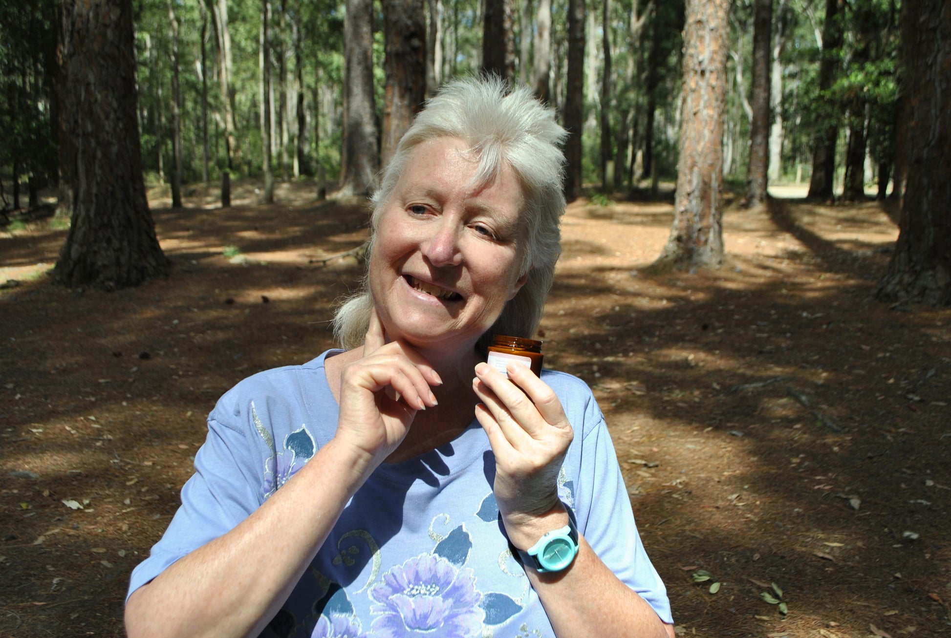 Close-up of person using The Oily Woylie Wound & Chafing Cream on their neck while outdoors in the forest — natural healing and anti-chafing cream made with essential oils.
