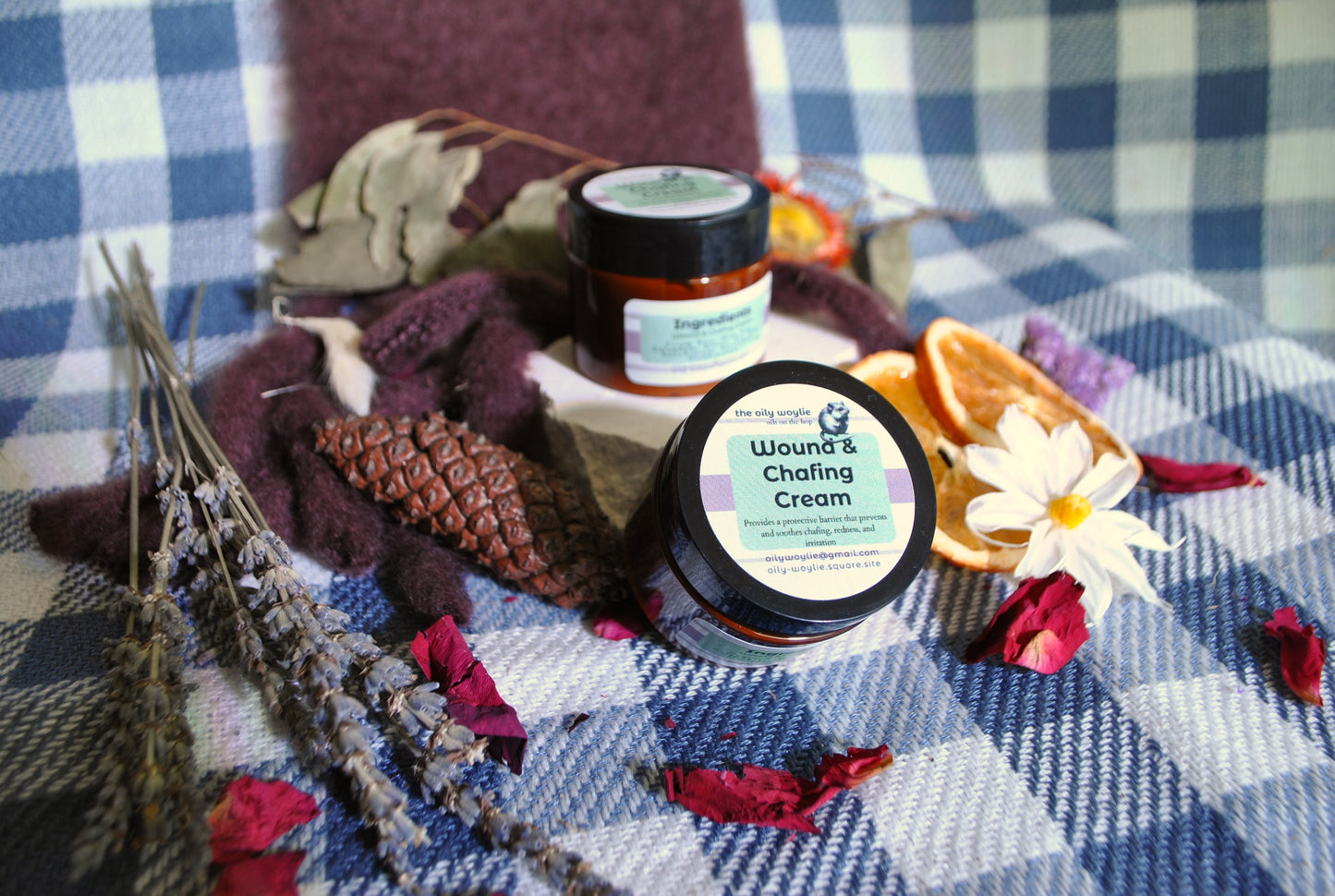 Wound & Chafing Cream jar, natural cream to soothe skin irritation and chafing on a checkered fabric background with flowers and leaves.